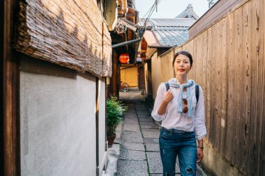 zarif kadın seyyahı Japon geleneksel sokakta yürüme ve ahşap evin içine arıyorum. Genç Turizm şehir Kyoto Japonya Seyahat Rehberi takip.