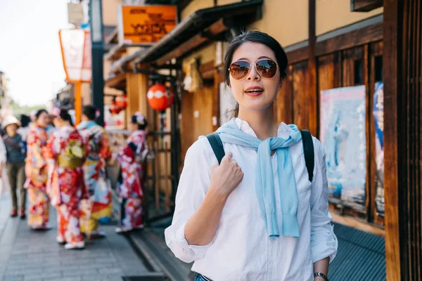 ジョイフル観光は バック グラウンドで着物を着ている若い女の子に日本の通りを歩いてします バックパッカーに有名な京都の観光スポット 若い旅行者が日本で平和な町を訪れる — ストック写真