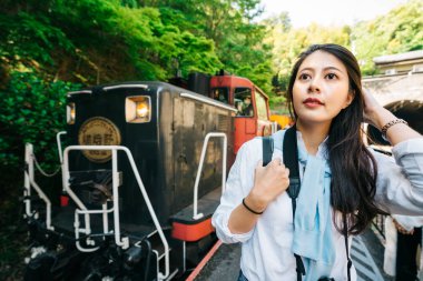 trenden indi ve Japonya'da ünlü trenin önüne ayakta zarif kadın seyahat. Kyoto yaşam tarzı seyahat. Genç turizm platformu üzerinde mavi gökyüzüne bakarak.