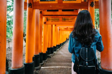 arkadan görünüşü güzel siyah uzun düz saç ayakta kırmızı Torii ile Asyalı kadın. seyahat backpacker yaşam tarzı içinde Japonya. 