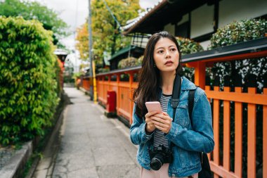 kadın turist sonraki gezi yer aramak için cep telefonu kullanarak. Ünlü Japon hedef üzerinde yürüyen turist Asya'da. Asyalı kız Kyoto cep telefonu kamera uygulaması kullanarak.