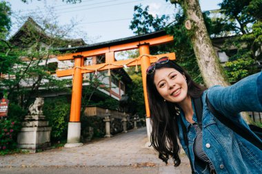 zarif gezgin onun baş ve alma selfie yakın ile moda güneş gözlüğü koyarak. cep telefonu ile alarak fotoğraf gülümseyen backpacker tatil selfie mutlu kadın. Kyoto tapınağını ziyaret.