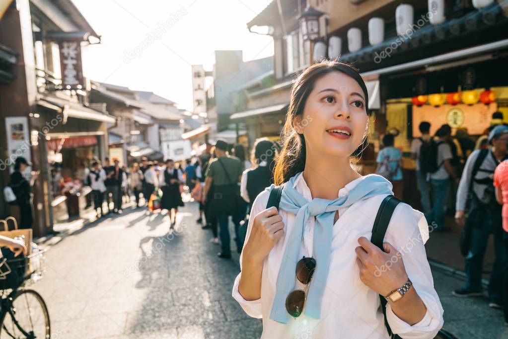 beautiful traveler standing on the teeming street in Japan and finding some street food to eat. Japanese specialty food sell on the food stand. Japnese people holiday lifestyle in teeming town.