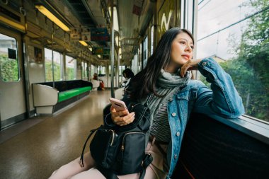 güvenmek üstünde belgili tanımlık pencere ve merakla metro görünümünde dışında seyir zarif Bayan. Sabah işe gitmek için mutlu banliyö tren seyahat zevk. Asyalı kadın tarafından geçen manzarayı.