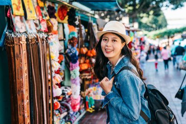 güzel Bayan kemer satıcı önünde duran ve kocası için hediye seçmek. Genç Gezgin Kamera gülümseyen La kız turist yüze ünlü Meksikalı sokakta Hediyelik eşya satın alma.