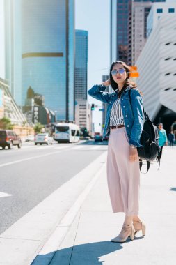güzel kadın ayakta fotoğrafı tam uzunlukta yol yanında bekleyin ve uzun saçları hareketleri. Gün olması ve şehirde alışveriş Asya Bayan. çekici kız tatil kavramı keyfi.