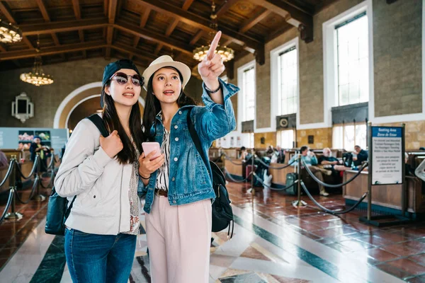 Gioiosi Viaggiatori Femminili Indicando Segno Discutendo Modo Giusto Nella Stazione — Foto Stock