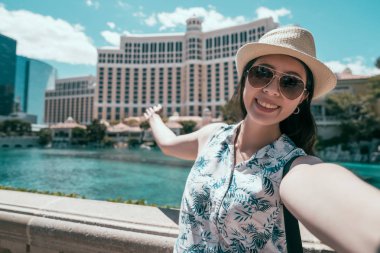 Çinli Genç kadın Amerika'da seyahat. Selfie alarak neşeli Bayan turist hotel las vegas ile kendini portait. yüze kamera gülümseyen güzel gezgin.