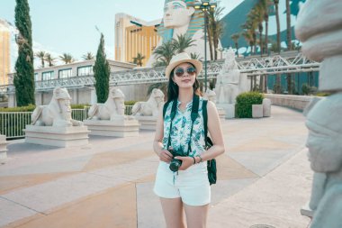 Neşeli Bayan turist ile kamera gezi Sfenks las Vegas. Asyalı kız açık havada seyahat eğleniyor. zarif kadın güneş gözlüğü ve hasır şapka mavi gökyüzü güzellik zevk.