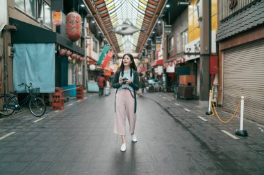 Bayan turist objektif adam kamera kapalı Pazar sabah yürüyüş tutarak tam uzunlukta fotoğraf. Balık balon içinde kapalı geleneksel çarşı Osaka çatıda asılı. Japonya'da gezi.