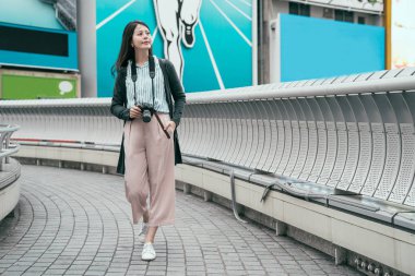 tam uzunlukta genç bayan fotoğrafçı fotoğraf makinesi ile köprüde yürürken rahatlatıcı. güzel Asya Bayan hobi alarak resim dslr fotoğraf makinesi. Şehirde tatil Japon kadın.