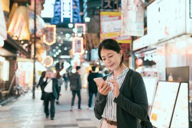 tsutenkaku sokakta Japon Bayan gecesi. Kadın geceleri online harita app üstünde hareket eden telefon online arama. akşam yemeği için restoran bulma cep telefonu kullanan genç yolcusu.