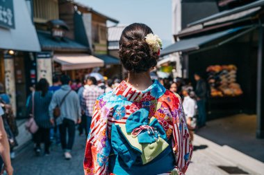 Arkadan Görünüş güzel Japon bayanın kimono ve mavi yay ile iç içedir sokakta yürüyen bant üzerinde. Asya Japon kadın yaşam tarzı. güneşli günde yürüyüş renkli elbiseli Genç kız.