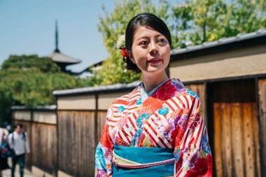 sokakta, arka planda uzun boylu pagoda ile çiçek deseni kimono ayakta giyiyor turist. Asya Genç Bayan kimono bornoz güneşli günde çalışıyor. kız gezgin Pagoda Kyoto ziyaret edecek.