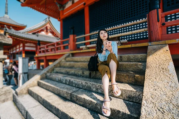 旅客坐在楼梯上放松后参观寺庙 并考虑下一个观光景点 年轻的游客使用在线导游应用程序体验京都日本 年轻女孩自行概念 — 图库照片