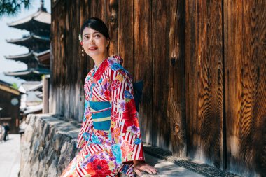 Çiçek desen kimono Kyoto ünlü pagoda ziyaret ettikten sonra ağacın altında oturup rahatlatıcı giyiyor turist. Genç gezgin Japonya Seyahat Rehberi için bekliyor. Asyalı kadın deneyimi Japonya kültür.