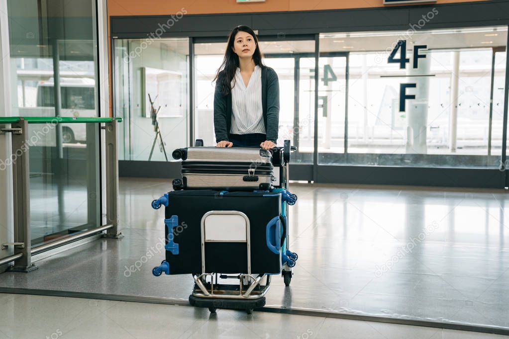 young japanese girl going study abroad leaving her country. cute student walking in airport alone with many luggages. elegant lady finding the sign of the airplane counter.
