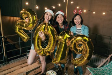 Genç kızlar gece partide çatıda 2019 balonlar gösterilen. arkadaş grubu Noel şapka neşeyle açık gülümseyen eğleniyor. Yeni yıl kadar geldiğin için moda Asya bayanlar ecited.