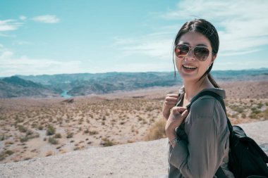 Genç kız gezgin hoover Barajı yaban hayatı seyahat özgürlüğü seviyorum. Bayan turist taşıma çantası ve yüz güneş gözlüğü ile kamera çekici bir gülümseme için. tatil olan kadın.