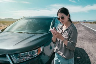 Seyahat tatil kira için Smartphone online kullanarak araba paylaşım rideshare cep telefonu app Genç Asyalı kadın. Güneşli mavi gökyüzü ile afiş panorama. Teknoloji aygıt.