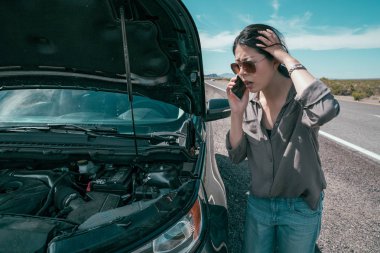 kırık araba kadın sürücü deli. Genç Asyalı kız bakmak motoru açmak ve karışık hissediyor. Acil durum yardım hizmeti boş karayolu üzerinde ile telefonda konuşurken endişe Bayan