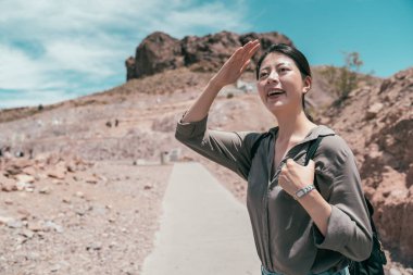 Neşeli gezgin hoover Barajı Nevada'da bulmak çölde duruyor. Genç Asyalı turist eller güneş ışığı güneşli bir günde yüz için kapak. Yalnız seyahat Amerika yaşam tarzı çekici kadın.