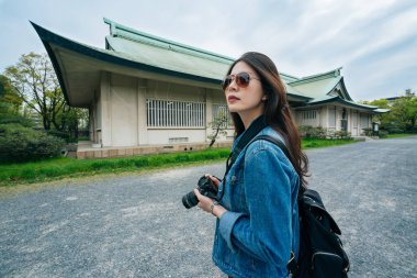 Kamera elinde tutan ve eski Japon Osaka'da inşa çekim Genç kız turist portresi. Hipster kadın sahada retro film kamera ile fotoğraf çekmek. Backpacker ziyaret jp.
