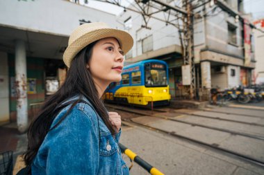 Tren geçmek için bekleyen ve trafik lambasından tren geçmeye hazır arıyorum Genç kız seyahat. Zarif Bayan turistik backpacker gezi Japonya'nın osaka yalnız. kadın merak görmek şehir.