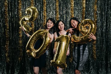 moda kızlar yeni yıl ve Noel arifesi altın sayı balonlar 2019 tutan gece kulübünde kutluyor. Asyalı güzel bayanlar kamera gülümseyen giymiş seksi parti elbiseler yüz. Gençler Kulübü tadını çıkarın..