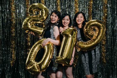 Grup Asyalı arkadaşıyla birlikte yüz kamera 2019 altın balonlar gösteren sarılma. Genç kızlar yeni yıl ve Noel arifesi gece kulübünde birlikte kutluyor. çekici seksi parti kadınlar gece hayatının tadını çıkarma.