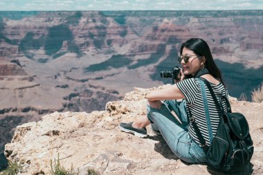 çöl dağ kum üzerinde oturan ve şaşırtıcı fotoğraf görünümü alarak mutlu kadın. Genç kız seyahat objektif adam tatile doğa yaşam keyfini çıkarın. Turizm Büyük Kanyon Ulusal Parkı.