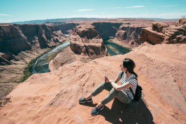 Genç turist ziyaret at nalı grand canyon öz Tur rehberli. dağ dinlenme üstünde oturan kadın Asya uzun yürüyüşe çıkan kimse. Bayan holding cep telefonu görünümü gezi rahatlatıcı.