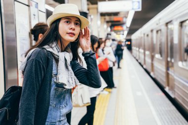 Bayan turist merakla platformda yeraltı tren beklemekten arıyorum. Metro ve tren istasyonuna geldi. insanlar içeri girmek hazır metro yanında ayakta.