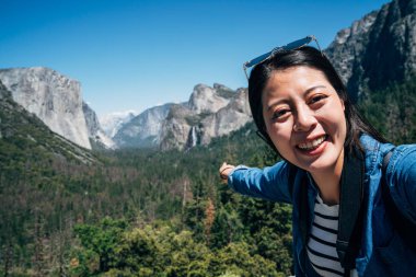 kadın uzun yürüyüşe çıkan kimse selfie sevinçle işaret parmağı şelale doğa görünümüne alarak kamera arıyorum. Genç Asyalı backpacker neşeyle dağ yosemite Milli Parkı, hiking. kadın turizm seyahat.