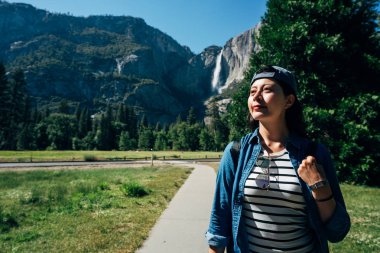 Uzun yürüyüşe çıkan kimse kadın yüksek dağın arka planda yosemite Milli Parkı ile orman yolundaki yürüyüş şapkalı. kendine güvenen bayan gezgin vahşi doğa yaşam tarzı konsepti yaz aylarında tadını çıkarın. Asya seyahat ABD.