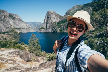 Asya backpacker yosemite Milli Parkı neşeyle selfie güzel doğa o shaughnessy Barajı ile alarak ziyaret edin. Genç kız turizm san franisco ABD yaz tatil seyahat gülümseyen çekici.