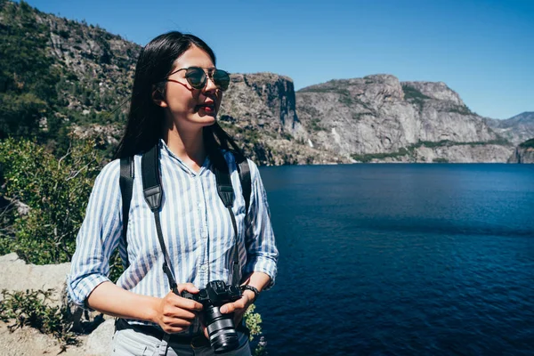 Bayan o'shaughnessy Barajı manzarayı kamera tutarak güneş gözlüklü Asyalı Çinli Bayan fotoğrafçı. Genç kız uzun yürüyüşe çıkan kimse seyahat yosemite Milli Parkı içinde. mavi göle doğada gezi.