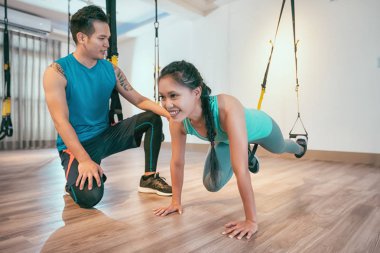 Asyalı kadın toplam vücut direnç egzersiz spor salonunda kişisel antrenör eğitim gerçekleştirme. Sportif kız Elastik ip ile tekme bacaklar egzersiz yapmak. sporcumuz sağlık kulübünde çalışıyor.