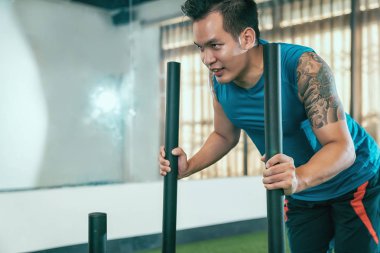 Erkek öğrenci itmeye hazır sopa tutan ups egzersiz ile yorgun bir yüz. sportif delikanlı sevinçle spor olarak çalışma yapmaya konsantre. Tam spor kulübü sınıfta çevresinde aynalar.