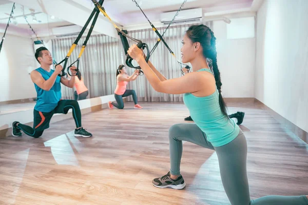 一群年轻人正在室内训练 Trx 运动俱乐部的全面身体抵抗锻炼课 亚洲妇女和男子正在健身房锻炼 — 图库照片
