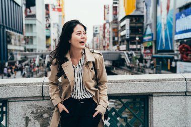 güzel kanal arıyorum iş işçi neşeyle gülerek Nehri üzerindeki köprüde duran görüntüleyin. Küpeşte dotonbori osaka Japonya güvenerek hanım. woamn akıllı rahat kıyafetli.