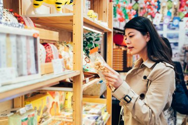 Yerel özel dükkanı dotonbori osaka Japonya içinde çocuklar için Aperatif seçerek Genç Japon anne. Asya Anne gıda çerezleri ailesi için satıcı, eser sonra satın alma. güzel Bayan işareti okuma.