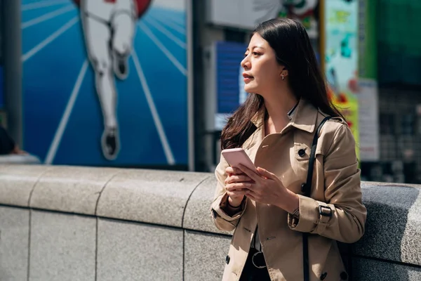 日本の携帯電話ビジネス女性支払いやオンライン ショッピングのスマート フォン モバイル アプリ上にテキスト メッセージ 都市生活立っているアジアの女の子幸せ有名なランニング男サインの前に橋の上 — ストック写真