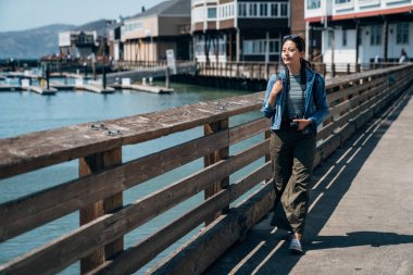 tam uzunlukta fotoğraf güzel bir deniz manzarası gezi bağlantı noktasında ahşap Küpeşte boyunca yürüyüş zarif Asya seyahat. Genç kız turist ziyaret iskele san francisco Kaliforniya 39.