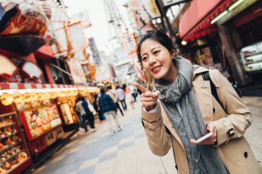 Online harita tutarak ve Japonca yerel Izakaya öğle yemeği için restoran arama neşeli kız turist. Genç kadın gezgin neşeyle işaret parmağı iç içedir sokak osaka Japonya üzerindeki hedefe.