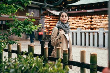 Zarif Bayan tenmangu Japonya'nın osaka huzurlu yeşil bahçesinde arıyorum. her zaman bir servet sopa duvara asılı olan tarihsel Japon shinto dua grace dilek umut ahşap tahta kırmızı ip tarafından.