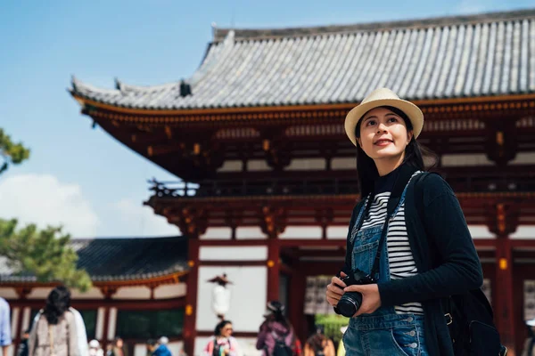 Bayan turist Todaiji nara Japonya ziyaret etti. Genç kız seyahat fotoğrafçı hobi kamera seyahat dünya çapında tutarak. temiz mavi gökyüzü ayakta kapısı önünde görünen kadın objektif adam
