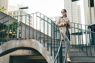 Genç güzel kolej kız öğrenci kahve ile merdivenlerden aşağı gidiyor. güneş gözlüğü neşeli okul ders sonra yürüme zarif zeki Asyalı kadın. kat rahat eğitim güzel Çinli kadın.