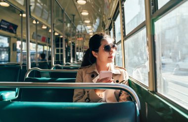 Cep telefonunu süre commuting toplu taşıma kullanarak genç Genç kız. Asyalı kadın güneş gözlüğü görünümü otobüs pencereden dışarı bakıyor. Boş Tramvay teleferik san Francisco.