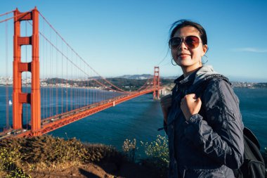 Golden gate köprüsü mutlu seyahat San Francisco ABD kadın kameraya gülümseyen güneş gözlüğü. Manzarayı ünlü seyahat işareti mavi gökyüzü deniz genç Interracial hipster Bayan gezgin.